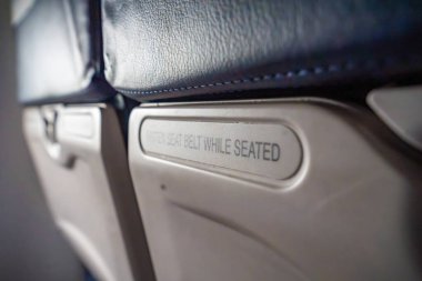 Bir uçakta otururken kemerlerinizi takın yazan tabela yakın plan. Hava yolculuğu rutini, güvenlik talimatları ve ulaşım farkındalığı. Yüksek kalite fotoğraf