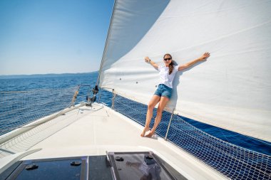 Bir deniz yolculuğu sırasında yelkenli bir yatın pruvasında duran genç bir kadın. Deniz yolculuğunda özgürlük, rüzgar ve düşünceli yalnızlık. Yüksek kalite fotoğraf