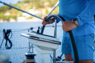 Hırvatistan yakınlarındaki seyir ve kontrol panelini kullanarak yelkenli bir yatı kullanan bir adam. Denizde hassasiyet, kontrol ve modern yelkencilik yaşam tarzı. Yüksek kalite fotoğraf