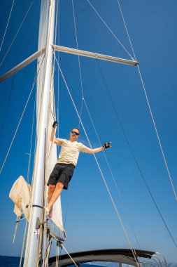 Yelkenli bir yatın direğine tırmanan adam, Hırvatistan yakınlarından ele geçirildi. Cesaret, özgürlük, yat hayatı ve deniz keşfi. Yüksek kalite fotoğraf