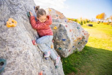 Oyun parkında yapay bir tırmanma duvarına tırmanan küçük bir kız güç ve koordinasyon geliştiriyor. Yüksek kalite fotoğraf