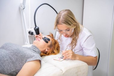 Modern güzellik salonunda ultraviyole lamba kullanarak kirpik uzatma işlemi. Kusursuz uygulama teknikli yenilikçi kırbaç geliştirme teknolojisi. Yüksek kalite fotoğraf