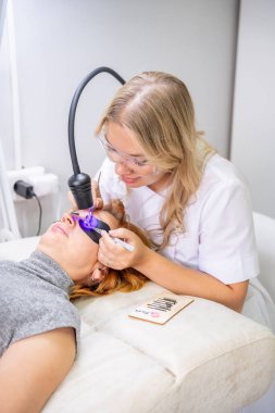 Modern güzellik salonunda ultraviyole lamba kullanarak kirpik uzatma işlemi. Kusursuz uygulama teknikli yenilikçi kırbaç geliştirme teknolojisi. Yüksek kalite fotoğraf