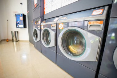 Budva, Karadağ - 25 Haziran 2025: Bir self-servis çamaşırhanesinde sıra sıra çamaşır makineleri. Ev aletleri perspektife göre hizalandı. Yüksek kalite fotoğraf