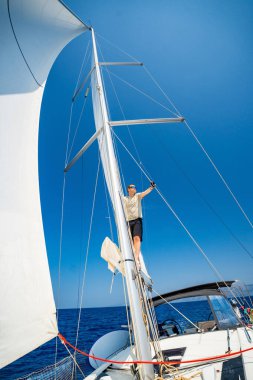 Yelkenli bir yatın direğine tırmanan adam, Hırvatistan yakınlarından ele geçirildi. Cesaret, özgürlük, yat hayatı ve deniz keşfi. Yüksek kalite fotoğraf