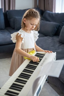Küçük kız evde piyanosunu dikkatlice temizliyor. Müzik yoluyla erken çocukluk eğitimi enstrümana özen, sorumluluk ve saygı içerir. Yüksek kalite fotoğraf
