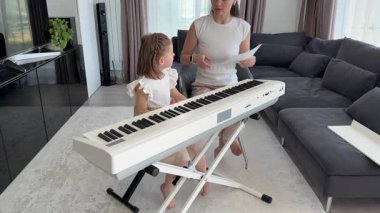 Oturma odasındaki küçük bir çocuk için özel piyano dersi. Kişisel müzik eğitimi yoluyla erken çocukluk gelişimi kavramı. Yüksek kalite fotoğraf