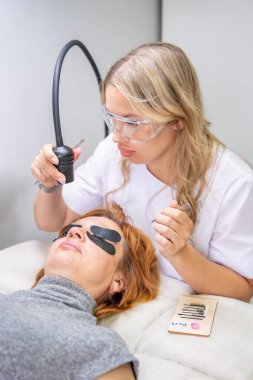 Modern güzellik salonunda ultraviyole lamba kullanarak kirpik uzatma işlemi. Kusursuz uygulama teknikli yenilikçi kırbaç geliştirme teknolojisi. Yüksek kalite fotoğraf