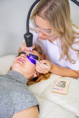 Modern güzellik salonunda ultraviyole lamba kullanarak kirpik uzatma işlemi. Kusursuz uygulama teknikli yenilikçi kırbaç geliştirme teknolojisi. Yüksek kalite fotoğraf