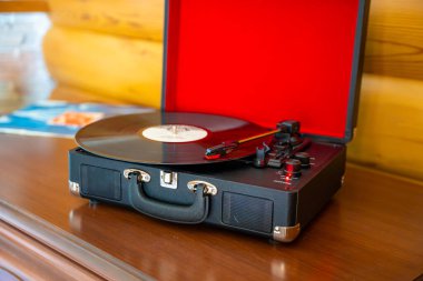 Klasik bavul tarzı plak çalar vinil plak çeviriyor. Retro müzik hareket halinde. İç mekanda nostaljik bir atmosfer yaratıyor. Yüksek kalite fotoğraf