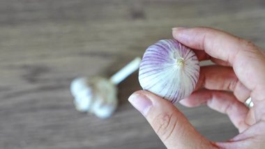 Bir elinde normal çoklu diş sarımsağı, diğer elinde Çin sarımsağı tutan kadın elleri. Malzeme karşılaştırması ve yemek seçimi kavramı. Yüksek kalite 4k görüntü