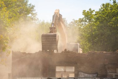 Kazıcı, şehir caddesindeki eski bir binayı yıkıyor. Kentsel yeniden yapılanma, yapısal parçalanma ve şehir mimarisinin dönüşümü kavramı. Yüksek kalite fotoğraf