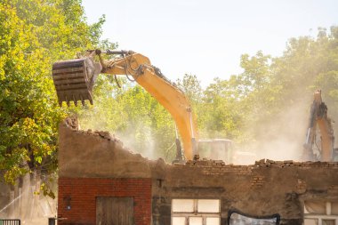 Kazıcı, şehir caddesindeki eski bir binayı yıkıyor. Kentsel yeniden yapılanma, yapısal parçalanma ve şehir mimarisinin dönüşümü kavramı. Yüksek kalite fotoğraf