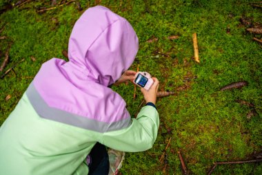 Çekoslovakya 'daki açık hava keşfi sırasında oyuncak kamerayla orman ortamını belgelendiren küçük bir kız. Erken çocukluk eğitimi, doğa eğitimi ve oyun yoluyla çevre bilinci..