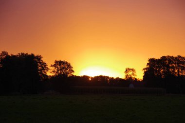 Almanya 'da çayırların ve tarlaların üzerinde renkli bir gökyüzü ile gün doğumu