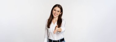 Smiling, friendly corporate woman extending arm for handshake, shaking hand, greeting business partner, standing over white background.