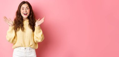 Şaşırmış, el çırpmış, gülümseyen, şaşırmış görünen, harika haberler alan, övülen, pembe arka planda duran mutlu güzel kız..