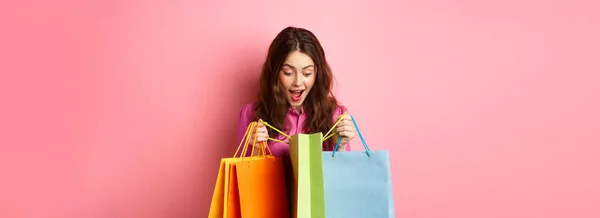 Aufgeregtes Mädchen Öffnet Einkaufstüten Und Keucht Erstaunt Schaut Sich Mit — Stockfoto