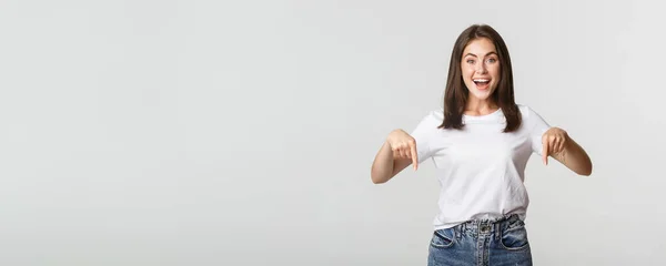 Zufrieden Lächelnd Brünettes Mädchen Zeigt Mit Dem Finger Nach Unten — Stockfoto