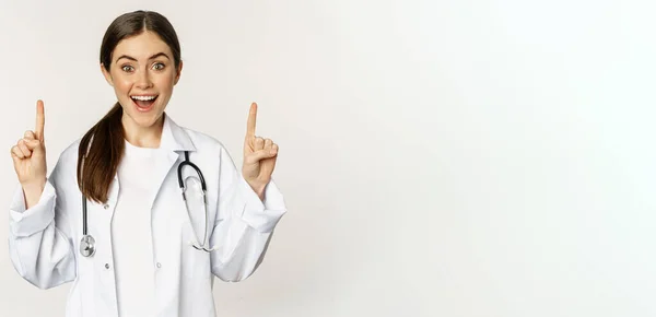 Enthusiastic Young Woman Doctor Smiling Pointing Fingers Wearing Hospital Uniform — Stok fotoğraf