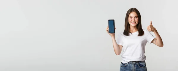 Zufrieden Lächelnde Attraktive Frau Zeigt Smartphone Bildschirm Und Daumen Hoch — Stockfoto