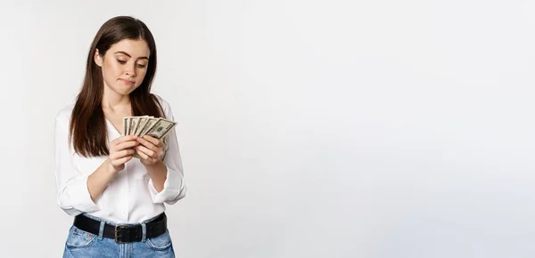 Sad Woman Counting Money Lacking Cash Standing Gloomy White Background — Φωτογραφία Αρχείου