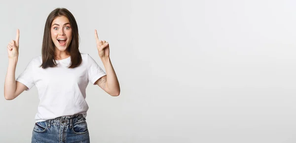 Atraktivní Usmívající Bruneta Dívka Ukazuje Prsty Nahoru Ukazuje Logo — Stock fotografie