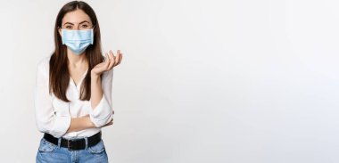 Güzel ve şık modern kadın portresi, beyaz arka planda duran covid-19 salgını sırasında tıbbi maske takıyor..