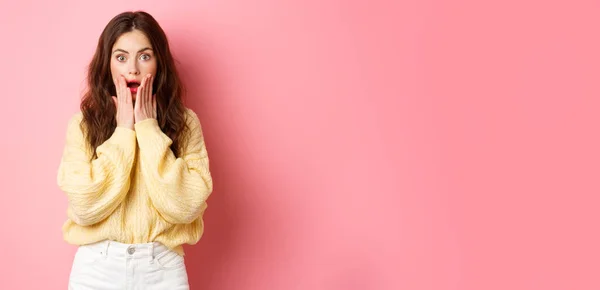 stock image Image of shocked and surprised brunette woman gasping, checking out big news, open mouth, holding hands on face, standing amazed against pink background.