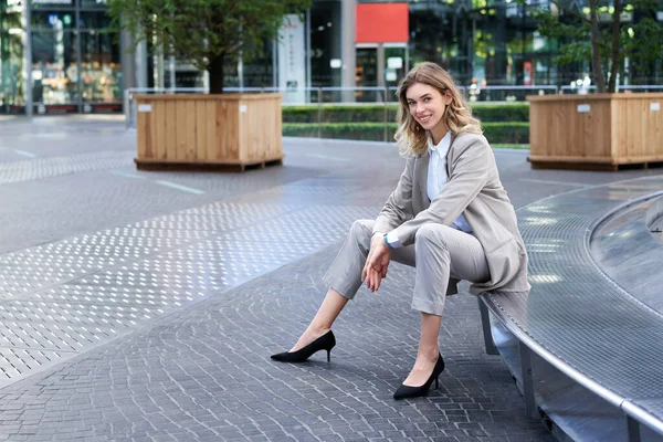 stock image Confident saleswoman in suit, sitting in city centre and smiling.