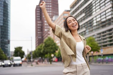 Mutlu Asyalı kadın portresi, dans ve mutluluk, zafer, zafer jesti, sokaklarda kutlama.