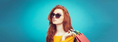 Alışveriş kavramı - portre genç güzel çekici Dişileştirilmiş kız kameraya alışveriş çantası ile seyir gülümseyen yakından. Mavi Pastel renkli. Kopya alanı.