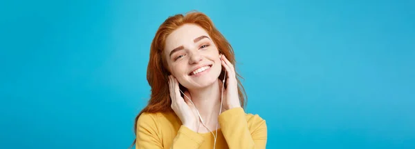 生活方式的概念 肖像的开朗快乐姜红头发的女孩喜欢听音乐与耳机快乐微笑对镜头 柔和的蓝色背景上的孤立 复制空间 — 图库照片