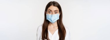 Covid-19 ve pandemik konsept. Coronavirus sosyal mesafesi sırasında tıbbi maske takan genç bir ofis kadını beyaz arka planda duruyor..