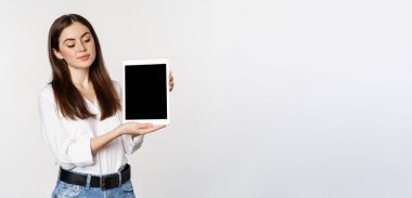 Tablet ekranı gösteren kurumsal bir kadının portresi, şirketin web sitesini gösteriyor, beyaz arka planda duruyor..