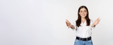 Enthusiastic laughing woman, smiling and stretching out arms forward, welcome you, greeting, standing over white background.