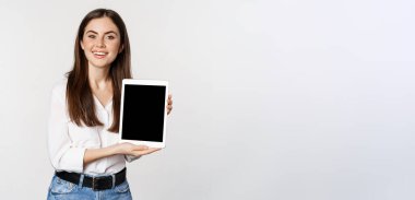 Portrait of corporate woman showing tablet screen, demonstrating company website, standing over white background.