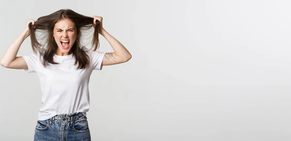 stock image Outraged mad young woman ripping hair on head and yelling angry.