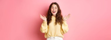 Şaşırmış, el çırpmış, gülümseyen, şaşırmış görünen, harika haberler alan, övülen, pembe arka planda duran mutlu güzel kız..