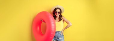 Stylish beach girl with swimming ring, laughing and smiling on summer vacation, sea trip, standing happy against yellow background.