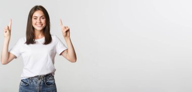 Çekici, gülümseyen esmer kız parmaklarını kaldırıp logoyu gösteriyor..