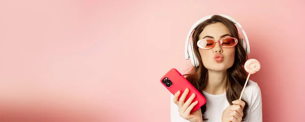 Gyönyörű Női Modell Hallgat Zenét Fejhallgató Gazdaság Lolipop Mobiltelefon Pózol — Stock Fotó