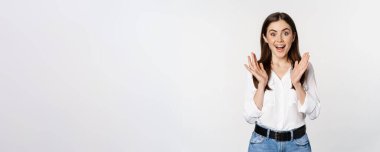 Enthusiastic laughing woman, smiling amused, clapping hands, applausing, standing in formal outfit over white background.