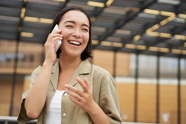 아시아인 여성은 전화로 이야기하고 중심가를 야외에서 포즈를 취한다 — 스톡 사진