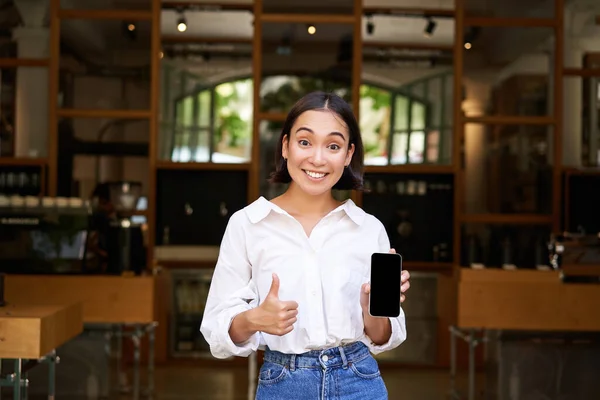 Entusiasta Chica Asiática Joven Camarera Café Mostrando Aplicación Teléfono Móvil —  Fotos de Stock