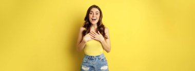 Portrait of enthusiastic, hopeful woman looking with yearning, smiling happy face, expecting smth, desire, standing over yellow background.