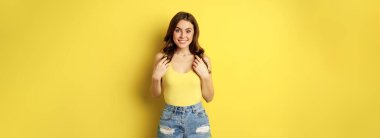Portrait of enthusiastic, hopeful woman looking with yearning, smiling happy face, expecting smth, desire, standing over yellow background.