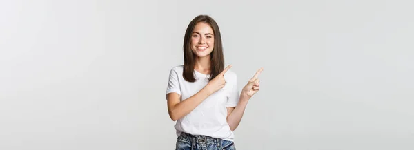 Satisfied Smiling Brunette Girl Pointing Fingers Upper Left Corner Showing — Stock Photo, Image