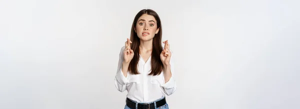 stock image Hopeful woman praying, cross fingers for good luck, begging, yearning smth, standing over white background. Copy space