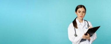 Image of professional woman doctor, physician with clipboard writing, listening patient at hospital clinic appointment, standing over torquoise background.